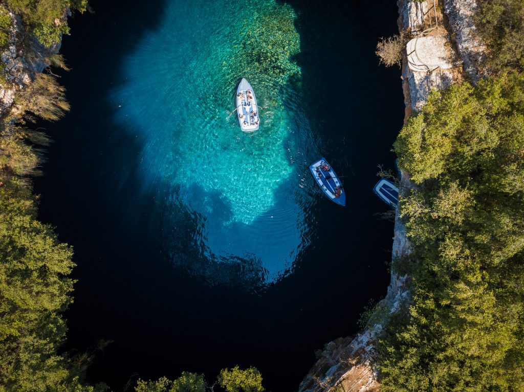 Couple of tour boats floating on the surface of clear water in cave Melissani