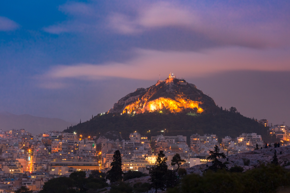 Mount Lycabettus towering above of the roofs of Old Town at sunset in Athens, Greece - kavalenkava / shutterstock