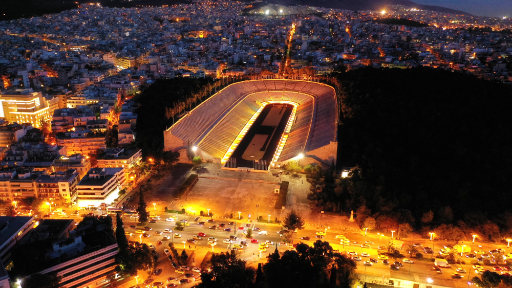 Aerial drone night shot of illuminated beautiful ancient stadium of Kalimarmaro or Panathenaic where first classic Olympic games were held at dusk with beautiful colours, Athens, Attica, Greece - Aerial-motion  / shutterstock
