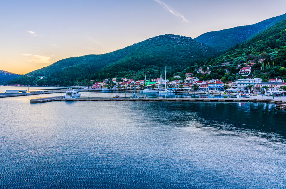 Panoramic view from the sea of the port of Sami with its moorings the port facilities and back the mountains illuminated by the sunset sun Kefalonia - Maekfoto / shutterstock